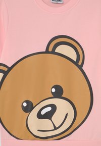 Rosa sweatshirt med ett stort tryck av en tecknad björnfot i brunt med svarta konturer. Slät material med ribbad rund hals och nederkant.