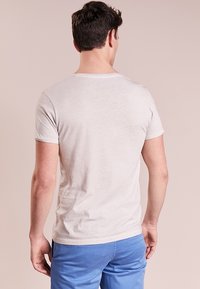 Bílý krátký rukáv, lehký materiál, přiléhavý střih, hladká textura, standardní kulatý výstřih, nošený s modrými šortkami.