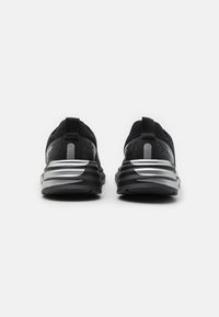 Scarpe da ginnastica nere con una tomaia textured, accenti argentati e un tallone decorato. Presentano una suola in gomma resistente e una linguetta per indossarle facilmente.