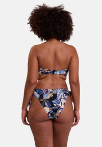 Ensemble de bikini floral avec un haut bandeau sans bretelles et un bas taille haute. Présente des motifs bleus, orange et beiges sur un fond noir.