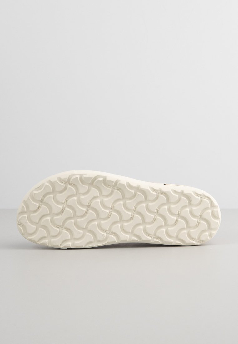 Sohle einer weißen Sandale mit gewelltem Profil und kleinen, eingeprägten "Birkenstock"-Logos auf der Oberfläche.