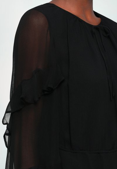 Black blouse with sheer ruffle sleeves, a round neck, and tie detail at collar. Made from lightweight, textured fabric.