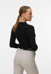 Must have ribadeeritud must pikkade käistega särk koos kaelusega, millele on lisatud heledahallid kohandatud püksid ja must vöö, omades sileda tekstuuri ja liigitatud siluetti.