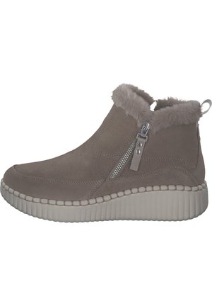 Bottes ankle en suede taupe avec col en fausse fourrure, zip sur le côté et semelle en caoutchouc blanc texturé. Forme arrondie et détails cousus.