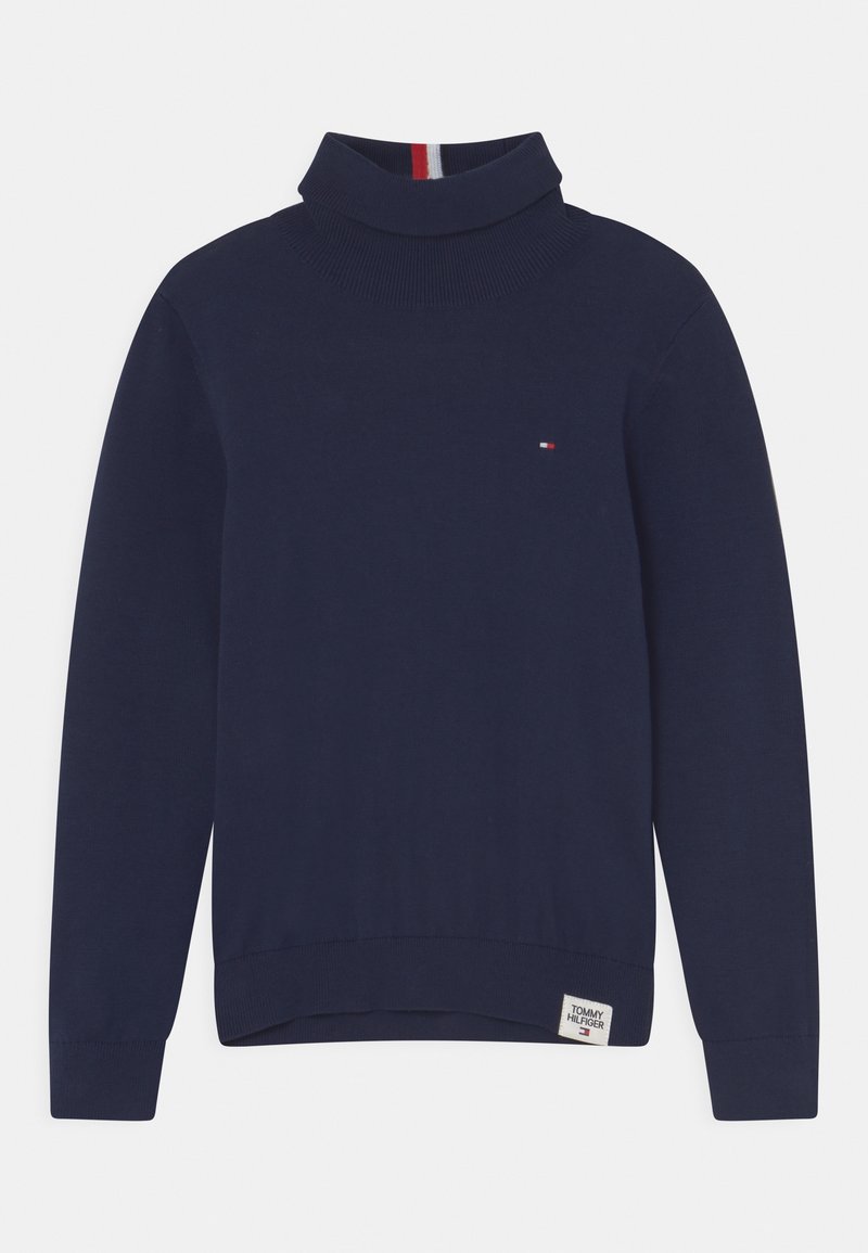 Pull à col roulé bleu marine à manches longues avec petit logo rouge, blanc et bleu sur la poitrine et étiquette Tommy Hilfiger à l'ourlet.