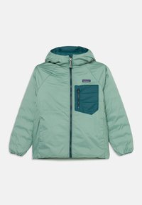 Svijetlozelena jakna s kapuljačom, zatvaranjem na zip i tirkiznom džepom. Ima glatku teksturu i elastične manžete. Dostupna je u pravokutnom obliku.