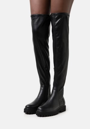 Černé kozačky nad kolena z hladké kůže se zapínáním na boční zip a texturovanou gumovou podrážkou s výrazným vzorem běhounu.