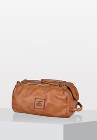 Borsa da toilette in pelle marrone con chiusura a zip, forma arrotondata, manico laterale e finitura texturizzata. Presenta un'etichetta con marchio sul fronte.