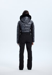 Czarna ocieplana kurtka z wzorzystym, szarym kapturem i częścią główną, w zestawie z dopasowanymi czarnymi spodniami. Tekstura gładka, z dopasowanym krojem.