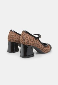 Leopard print high heels with a black patent leather trim and a chunky heel. Features a round toe and a Mary Jane strap.