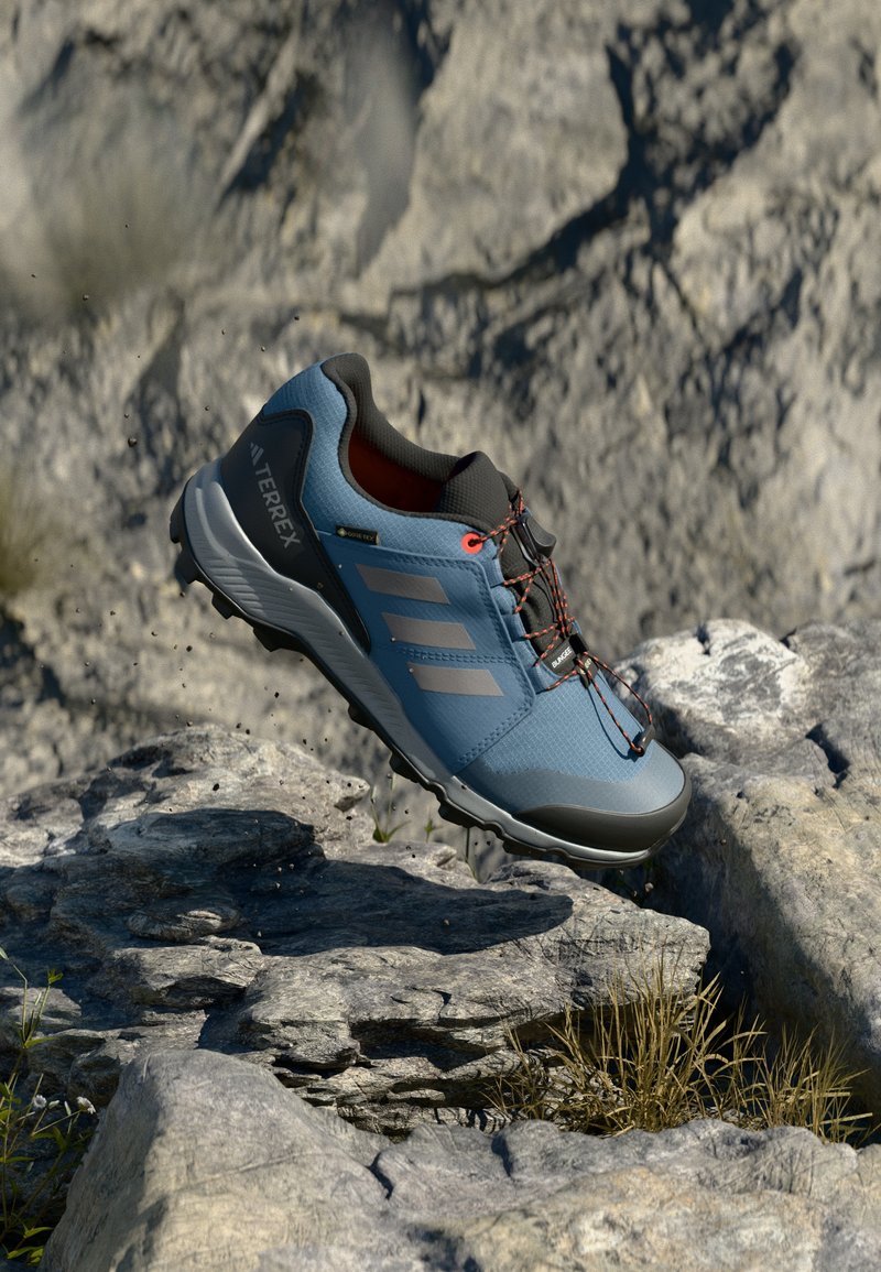 Sinine maastikujooksu king, hallide aktsentidega, musta kummist tallaga ja tekstuurse ülemise osaga. Omab punaseid paelu ja GORE-TEX sildiga veekindluse tagamiseks.