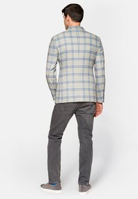 Jasnoszary blazer w kratę z niebieskimi liniami, dopasowany krój, średnia tekstura, zestawiony z ciemnoszarymi spodniami i casualowymi szarymi butami.