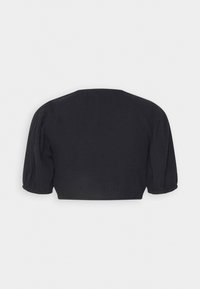 Top court noir avec un col rond, des manches bouffantes et un tissu texturé. Le dos est uni sans embellissements.