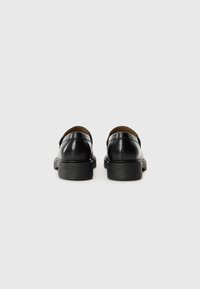 Schwarze Lederhalbschuhe mit glatter Oberfläche, runder Zehenpartie und robuster schwarzer Gummisohle. Einfaches Design mit minimalen Hardware-Akzenten.
