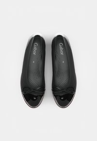 Black ballet flats with a shiny patent leather toe cap and bow detail. Soft leather upper with perforated insole for breathability.