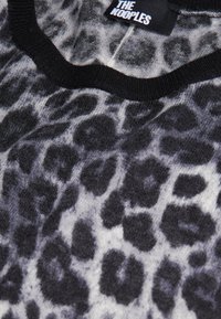 Pull en tissu doux avec un motif léopard noir et gris, col côtelé noir affichant l'étiquette "THE KOOPLES".