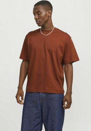 Braunes T-Shirt mit kurzen Ärmeln aus Baumwolle in lässiger Passform. Verfügt über einen runden Ausschnitt und subtile Nähdetails. Trägt man mit dunklen Denim-Hosen.