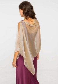 Châle beige transparent avec un design fluide, drapant élégamment une robe violet foncé. Présente une texture douce et des découpes ouvertes au niveau des bras.