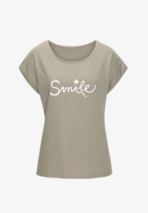 Camiseta gris claro hecha de tela suave, con un escote redondeado y mangas cortas enrolladas. En la parte delantera se muestra la palabra "Sonríe" en una escritura blanca.