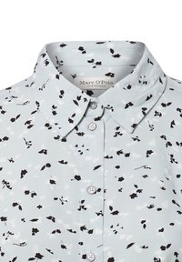 Maglietta a maniche lunghe di colore azzurro chiaro con un motivo floreale in bianco e nero, dotata di colletto e bottoni lucidi. Finitura in tessuto testurizzato.