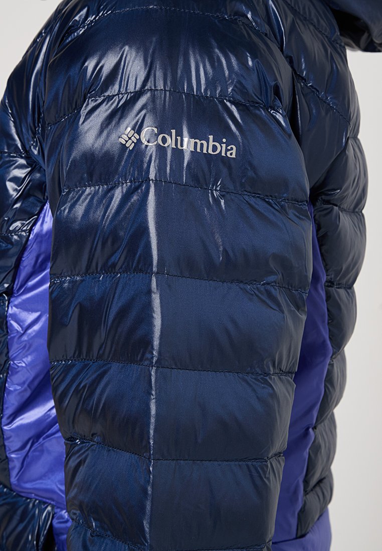 Doudoune bleu marine avec une finition brillante, dotée de sections matelassées horizontales et d'un panneau latéral violet, marquée du logo Columbia.
