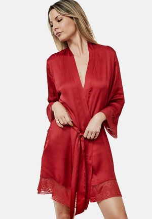 Robe en satin rouge avec de larges manches et une finition en dentelle au bas. La robe est ouverte, mettant en valeur sa texture lisse et sa couleur riche.