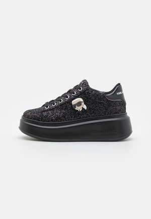 Baskets à plateforme noires pailletées avec lacets et figure de dessin animé représentant un homme avec des lunettes de soleil sur le côté, marquage « Karl Lagerfeld » au talon.