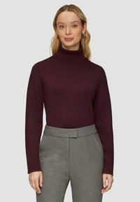 Bordeaux coltrui in een ribbelstructuur, gecombineerd met grijze op maat gemaakte broek met een vlakke voorkant en zijzakken.