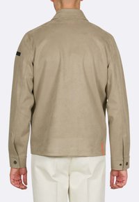 Giacca in suede beige con colletto, dettaglio nero sulla spalla sinistra e un particolare arancione all'orlo, con polsini abbottonati.