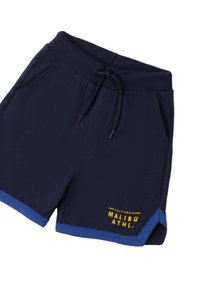Pantaloni sportivi blu navy realizzati in tessuto morbido. Presentano un elastico in vita con cordino, tasche laterali e un bordo blu con testo giallo.