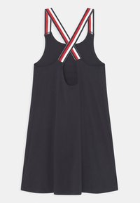 Granatowa sukienka bez rękawów z krzyżującymi się czerwono-biało-czarnymi paskami oraz małym wycięciem w kształcie klucza z tyłu.