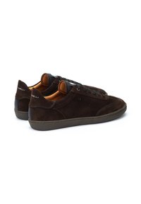 Zapatillas de ante marrón con un perfil bajo, punta redonda, detalles en negro y suela de goma texturizada con costuras en contraste.