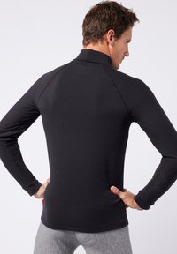 Black long-sleeve athletic shirt with a high collar and raglan sleeves, featuring smooth fabric and a fitted design.