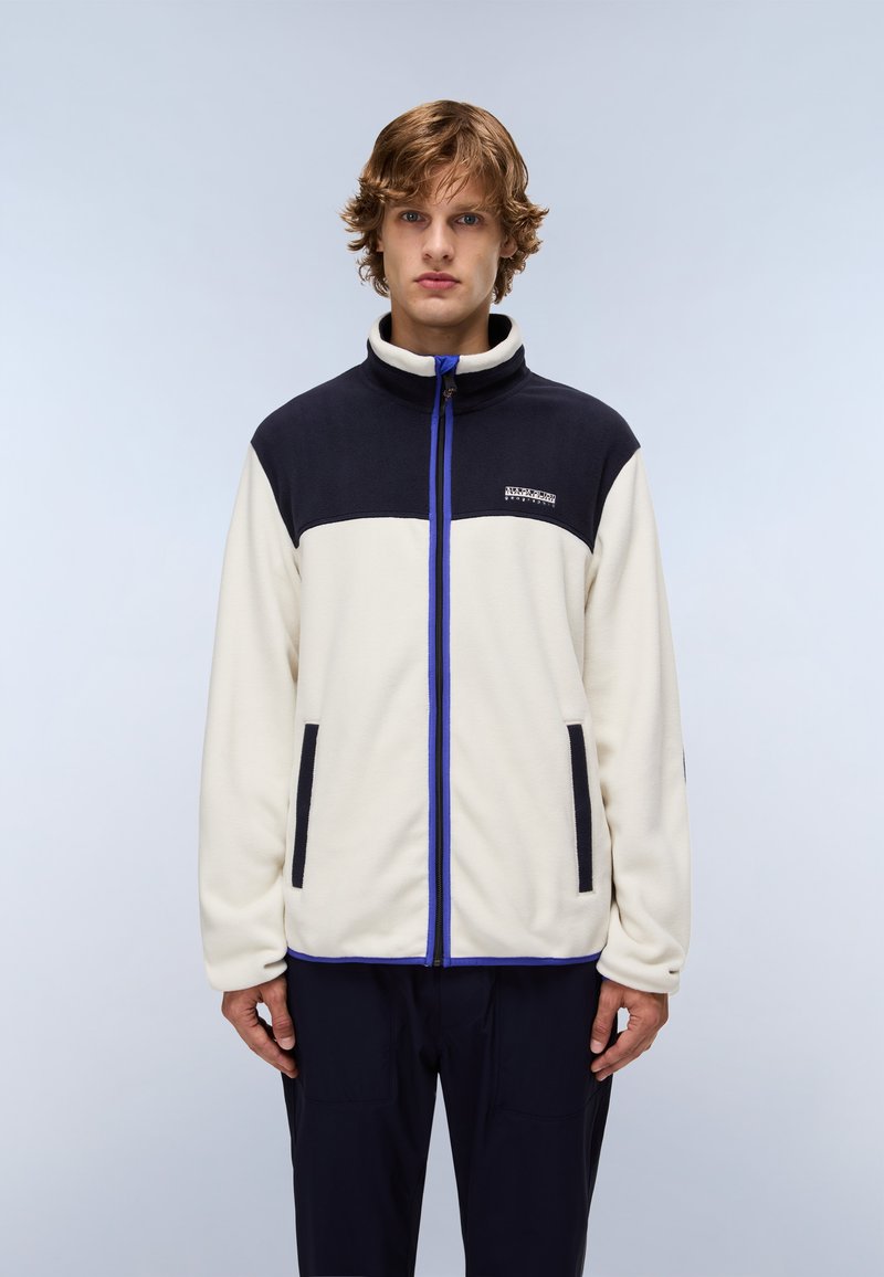 Giacca in pile con una parte superiore blu navy e una parte inferiore crema. Dotata di una cerniera completa, due tasche frontali e dettagli blu.