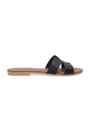 Schwarze Leder-Sandalen mit flacher Sohle, die zwei breite Riemen auf dem Fuß kreuzen und ein hellbraunes Fußbett aufweisen.