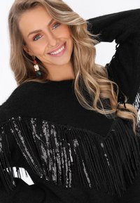 Maglione nero con frange e paillettes argentate lucide lungo il bordo inferiore. Tessuto morbido e vestibilità comoda. Maniche lunghe e scollatura rotonda.