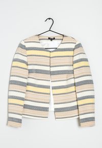 Texturerad blazer med rund halsringning, prydd med horisontella ränder i gult, grått och beige. Hänger på en svart krok mot en vit bakgrund.