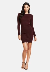 Burgundowa, prążkowana sukienka bodycon z długim rękawem, okrągłym dekoltem, dopasowanym krojem i mini długości, w połączeniu z czarnymi sandałami na obcasie.