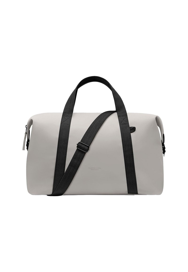 Bolsa de lona en gris claro con asas de cinta negra y correa ajustable. Cuenta con un cierre de cremallera y un detalle sutil del logo.