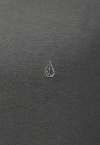 Γκρι μπλουζάκι κατασκευασμένο από βαμβάκι με λεπτή ριμπ ύφανση. Διαθέτει μικρό, τονικό κεντημένο λογότυπο στην αριστερή πλευρά του στήθους.