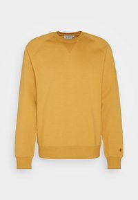 Pullover giallo senape a maniche lunghe con polsini e orlo a coste, scollatura a girocollo e piccolo logo sul polsino sinistro.