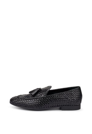 Mocassino slip-on in pelle intrecciata nera con nappine, suola piatta e tacco basso, mostrato in vista laterale su sfondo bianco.