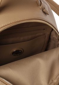 Interior de un bolso de cuero marrón con tejido texturizado, que cuenta con un bolsillo con cremallera y un bolsillo adicional con ranura. Detalles en cremallera dorada.