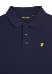 Navy-Polohemd mit texturiertem Finish, zwei Knöpfen am Kragen und gelbem gesticktem Adlerlogo auf der linken Brust.