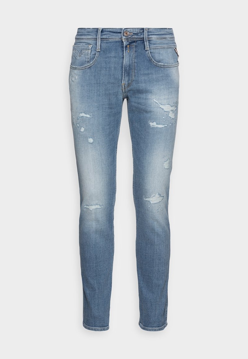 Jeans ajustados de color azul claro con parches desgastados y decoloración, que cuentan con bolsillos frontales y traseros y un cierre de botón y cremallera.