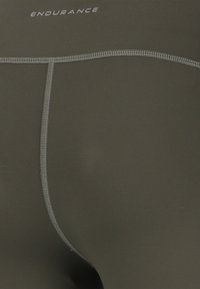 Donkergroene sportshorts van een gladde stof, met platte naden en het logo "ENDURANCE" boven de tailleband gedrukt.