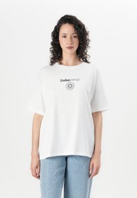 T-shirt de algodão branco com uma estampa a dizer "Energia Zodiaco" e um design circular. Corte descontraído e mangas curtas.