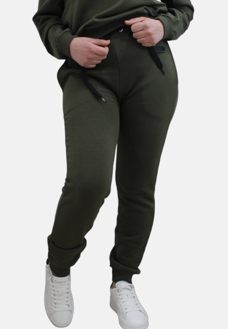 Pantaloni della tuta verde oliva con vestibilità affusolata, vita con coulisse regolabile e Tasche laterali, abbinati a sneakers bianche.
