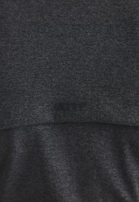 Ciemnoszary, teksturowany materiał z subtelnie wyhaftowanym logo "aimn" umieszczonym centralnie w pobliżu dolnej krawędzi widocznego obszaru.