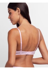 Pink bra with thin straps, a soft texture, and a hook-and-eye closure at the back, featuring a sheer panel design for added detail.